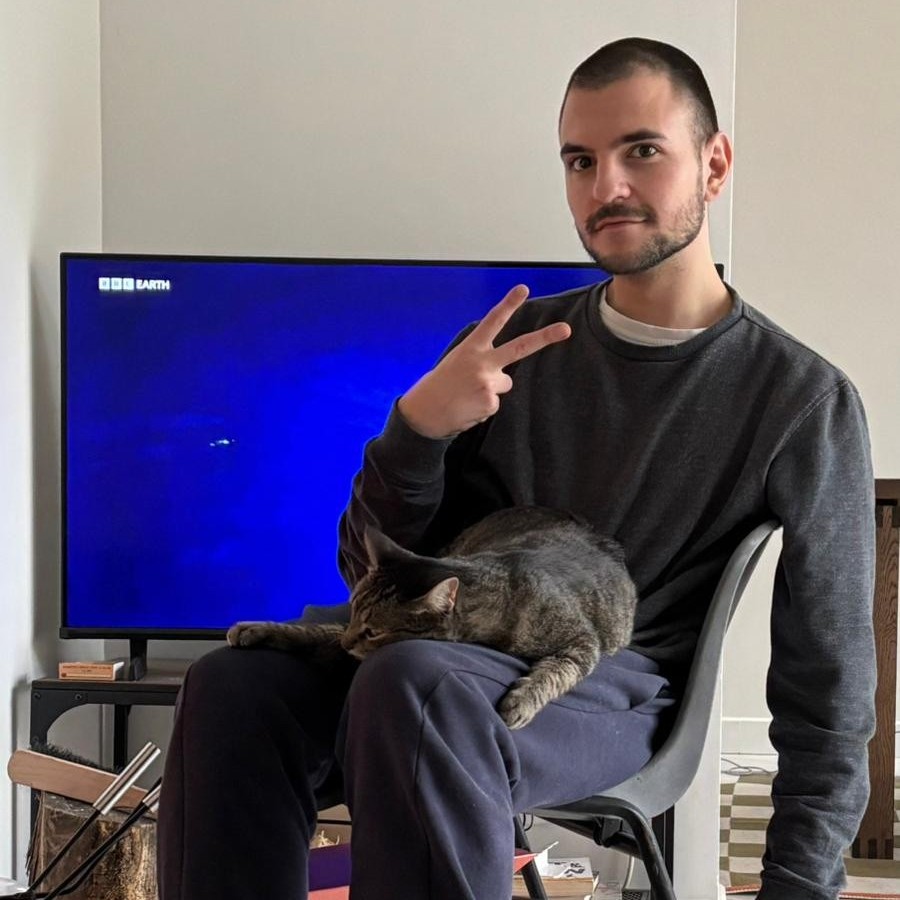 Relja Bojović, throwing a peace sign with a cat on his lap